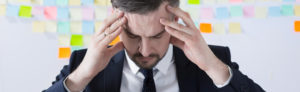 A businessman holds his head in his hands